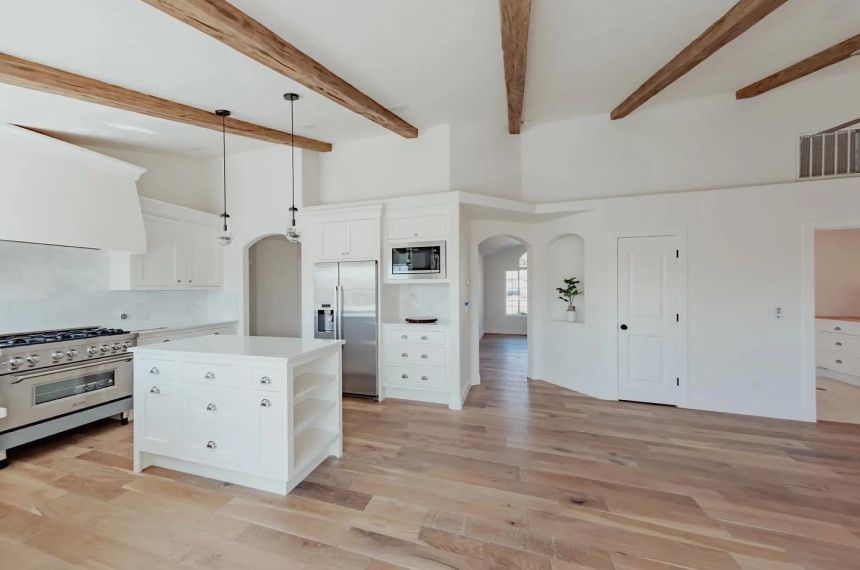 Open-concept kitchen with wood beams, island, and stainless range