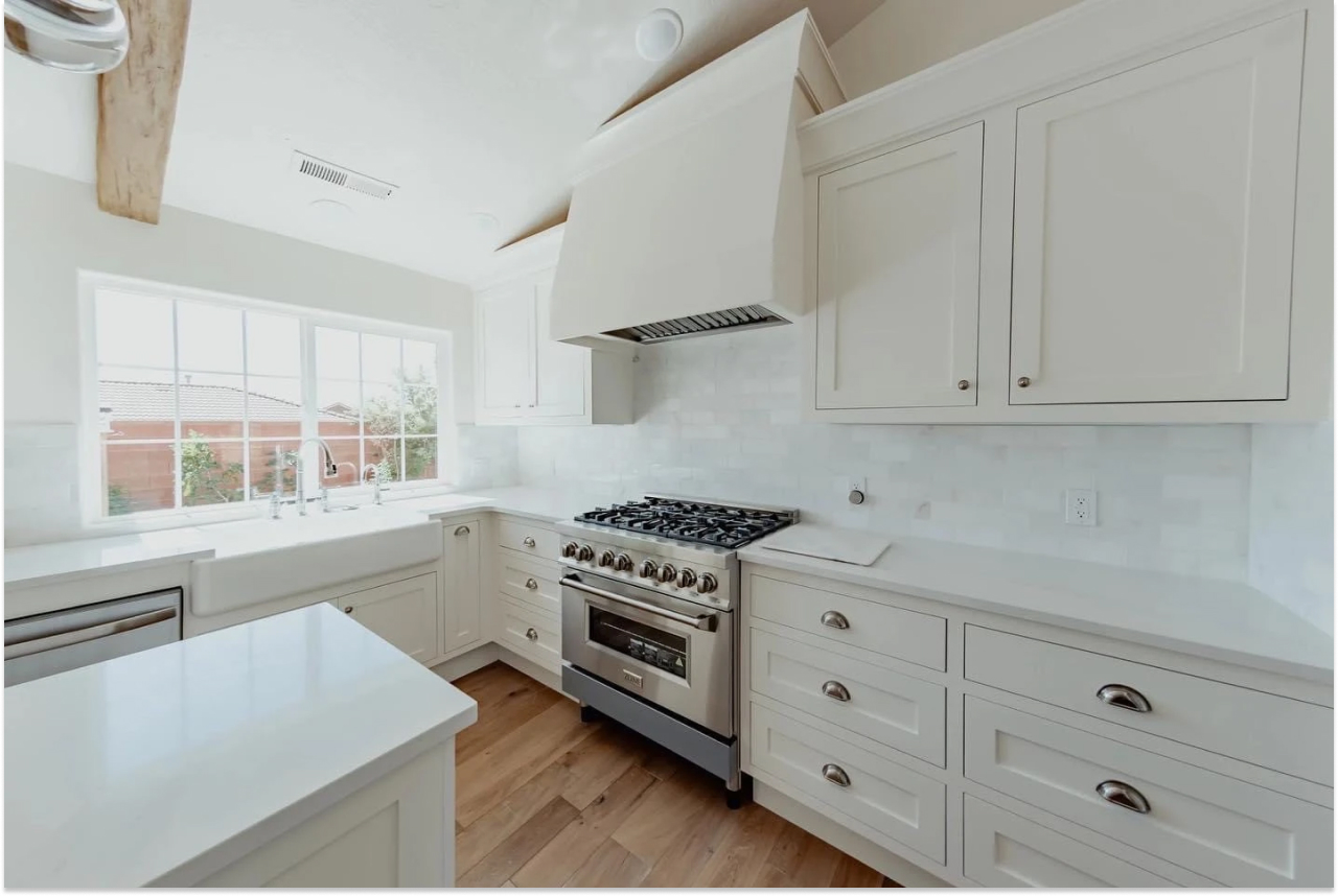 Bright custom white shaker kitchen with farmhouse sink and professional range