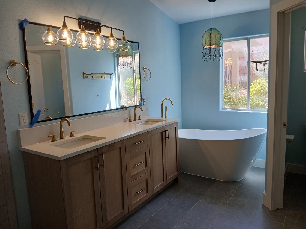Master bathroom with freestanding soaking tub, double vanity, and brass fixtures