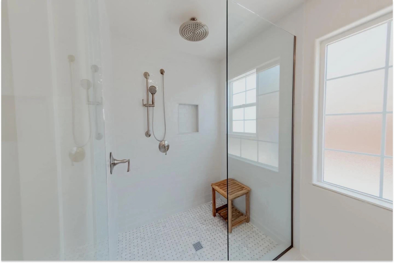 Walk-in glass shower with marble basketweave floor tile